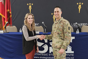 Ms. Missi Holley, SSI’s administrative officer, receives a coin from USAWC Commandant Colonel Donald Santillo.